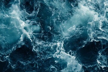 Aerial view of dark blue ocean water with white foam and waves.