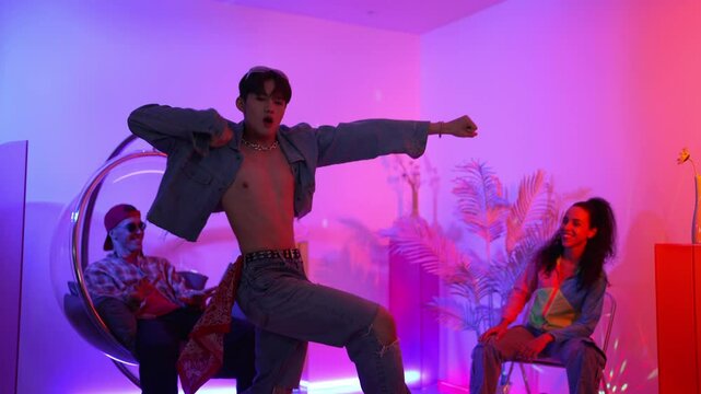Skilled asian dancer moving to modern music while multicultural friend sitting at chair. Professional performer dancing show energetic foot step while hipster team cheering and supporting. Regalement.