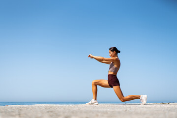 Fototapeta premium Fitness Enthusiast Stretching on the Seaside Cliff Edge