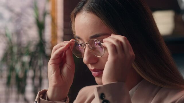 Gorgeous confident smiling Caucasian positive business woman girl female businesswoman lady entrepreneur worker puts on glasses eyeglasses vision sight optometry looking camera smiling indoors office