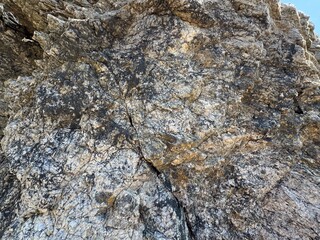 Mountain rock texture close-up background. Gray, black dark brown stone rock granite basalt texture background. Mountains surface. Close-up. Cracked broken crumbled. Rock texture wall.
