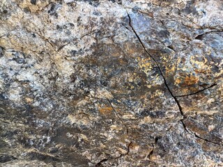 Mountain rock texture close-up background. Gray, black dark brown stone rock granite basalt texture background. Mountains surface. Close-up. Cracked broken crumbled. Rock texture wall.
