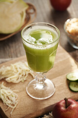 A cup of green cabbage and cucumber juice with red apples