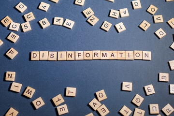 disinformation word arranged with wooden letter tiles on a blue background showcasing a...