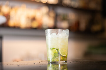 Process of making alcoholic cocktail mojito with lime juice. Male owner of establishment decorates cocktail glass with mint leaves. Ready-made drink for treat
