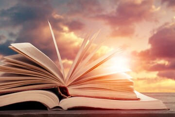 Scriptures on pages open book at bright sunset background
