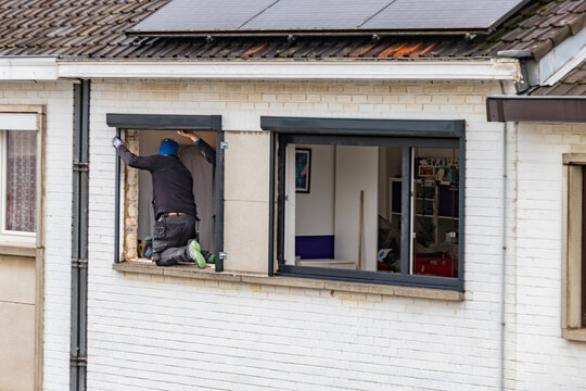 Ouvrier qui remplace un ch&acirc;ssis de fen&ecirc;tre &agrave; une maison