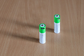 Two rechargeable batteries on wood close-up, green energy, Textured surface