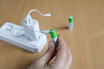 Textured surface, AA rechargeable battery pack in hand, charging from power adapter