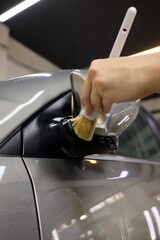 A person is cleaning a car windshield with a brush and water