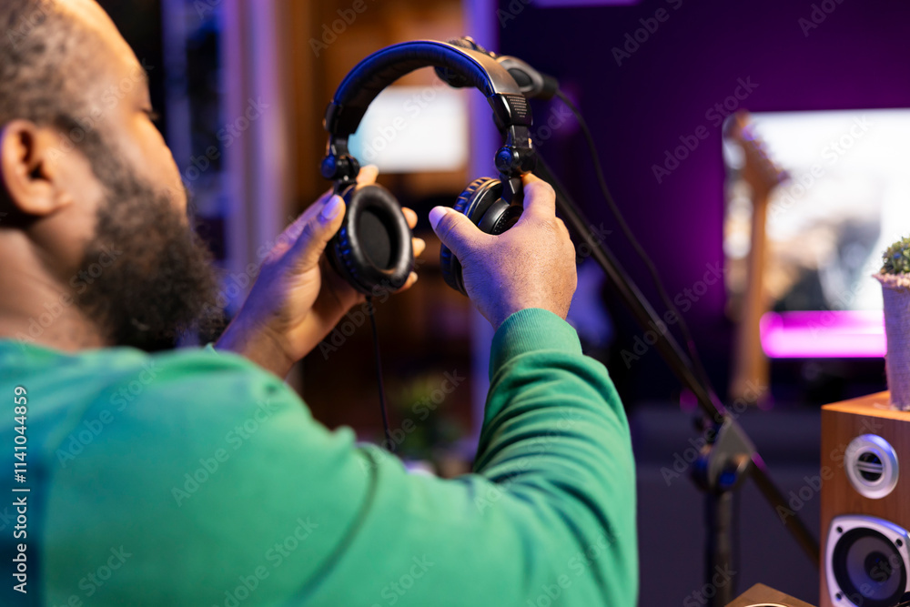 Poster trained audio technician picking up his headset for a recording session, mixing and mastering his tr