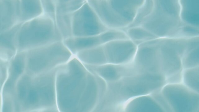 A close-up shot of clear blue water reflecting sunlight, forming gentle ripples and patterns on the surface. Water backdrop. Summer travel concept 