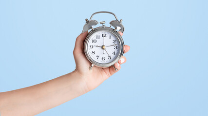 Girl hand showing alarm clock on white background, close up with copy space. Panorama