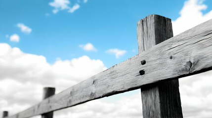 Low-angle close-up of a weathered wooden fence against a bright blue sky with fluffy clouds.