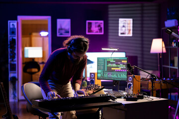 Confident singer playing new song on electronic piano keyboard in home studio, recording new music...