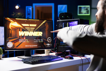 Joyous gamer celebrating after winning esports match during livestream with viewers, pointing to...