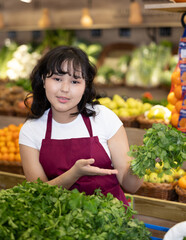 Portrait of friendly smiling female employee of a grocery supermarket with parsley