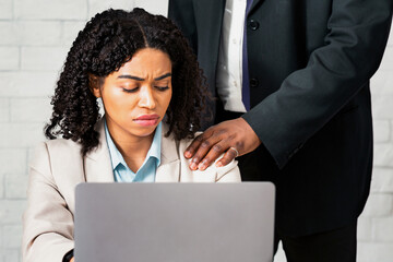 Workplace harassment concept. Young female secretary looking at boss's hand on her shoulder with...