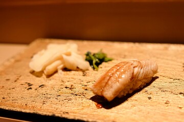 Anago nigiri (saltwater eel sushi) served with pickled ginger and wasabi leaf as part of an omakase lunch at Manten Sushi Marunouchi near Tokyo Station and the Imperial Palace - Chiyoda City, Tokyo