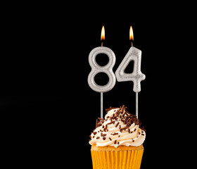 Birthday cupcake on black background - Number 84 shaped candles.