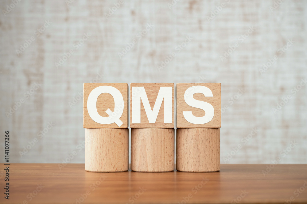 Poster there is wood cube with the word qms. it is an abbreviation for quality management system as eye-cat