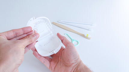 Manos sujetando alineadores dentales y estuche. Herramienta de extracción, cepillo de dientes y...