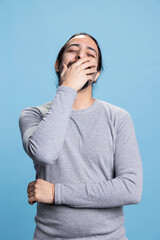 Middle eastern man feeling happy and amused with jokes in front of the camera, laughing and enjoying leisure time in studio. Young adult smiling and being joyful against blue background.