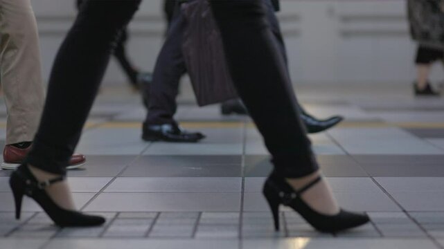 SLOMO Low shot of legs, feet and luggage of people walking in a crowded Tokyo subway train station. Captured at 120 frames per second.