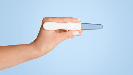 Unrecognizable woman holding blank pregnancy or ovulation test on pink background, closeup view. Copy space