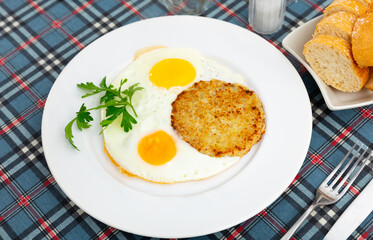 On plate are vegetable pancakes made from grated zucchini cooked with fried eggs sunny-side up eggs