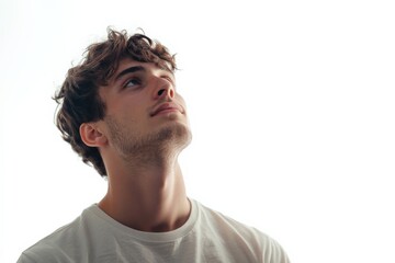 Fototapeta premium Young Man Gazing Upwards with Hopeful Expression Against a Bright Background