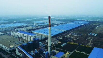 Corporate promotional aerial view showcasing a manufacturing facility with extensive blue roofing and industrial activity