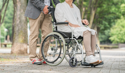 車椅子で公園を散歩するシニア・高齢者夫婦（介護）
