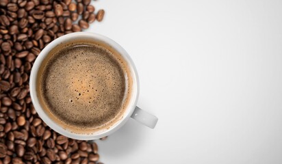 Cup of tasty hot coffee and coffee beans on desk