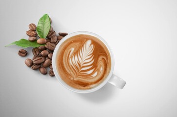 Cup of tasty hot coffee and coffee beans on desk