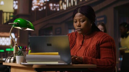 African american tutor preparing documents and learning materials for teaching session in school library. Clever professor providing academic resources for mentoring in the study area. Camera B.