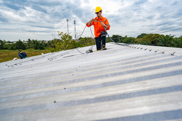 Technician in safety uniform and helmet kneeling on a rooftop, using a drill for precise installation work. A scene highlighting safety, professionalism, and technical expertise in construction.