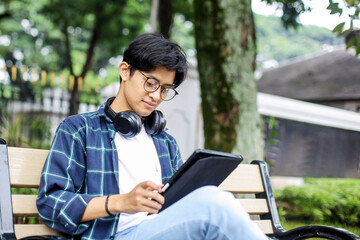 Young Man Using Digital Tablet on a Bench of The Urban Sidewalk