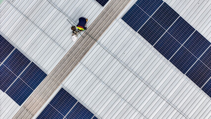 Aerial view of a rooftop with solar panels, showing a technician in safety gear performing maintenance. The scene highlights renewable energy, solar technology, and sustainable infrastructure.