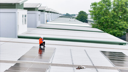 technician in safety gear inspects solar panels on a metal rooftop, holding a tool. The scene...
