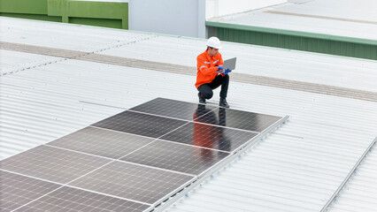 technician in safety gear inspects solar panels on a metal rooftop, holding a tool. The scene...