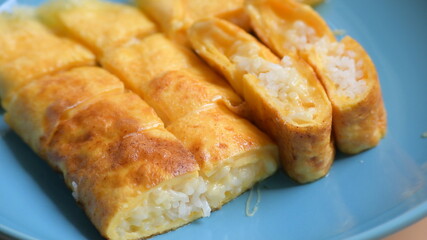 roll omelette stuffed with chesse and rice on blue plate, delicious food in the morning
