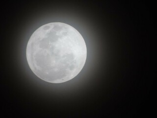 the moon is unclear, as though it is being seen through a camera lens that is not able to gather enough light. The object is in the night sky, so it looks like it's part of the stars and planets,