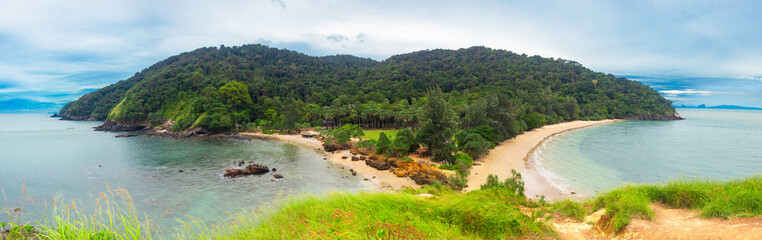 View curve of sand beach with many rocks, green mountain and blue sky background, Laem Tanod Viewpoint as the location of the Mu Ko Lanta National Park, Krabi province, Thailand.