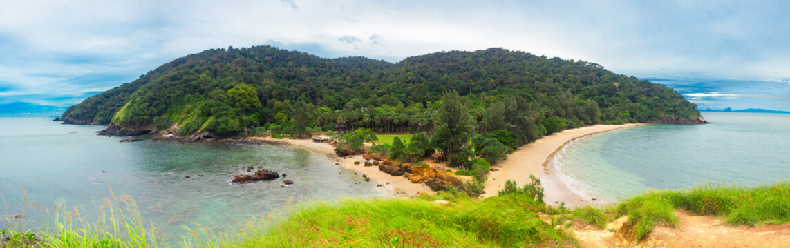 View curve of sand beach with many rocks, green mountain and blue sky background, Laem Tanod Viewpoint as the location of the Mu Ko Lanta National Park, Krabi province, Thailand.