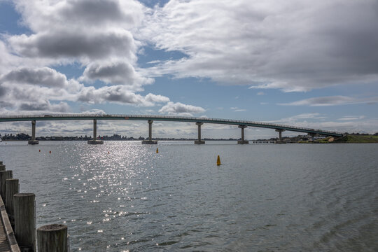 The curved Hindmarsh Island road bridge spanning the Murray River between Goolwa and Hindmarsh Island in the Coorong, under a threatening sky in this photo taken from Goolwa in South Australia.
