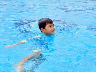 Asian school boy swimming at pool