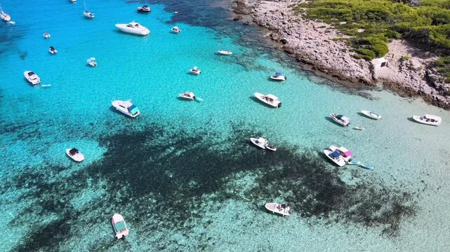Enjoy a tranquil day at Cala Agulla in Cala Rajada, Mallorca. The azure waters are dotted with boats, showcasing the region's natural beauty and serene atmosphere.