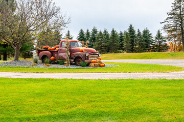 Old rusty truck decorated with pumpkins and cornstalks