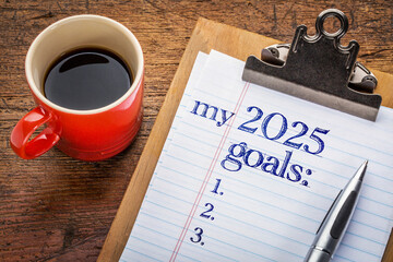 my 2025 goals list on clipboard and coffee against grunge wood desk, setting New Year goals and...